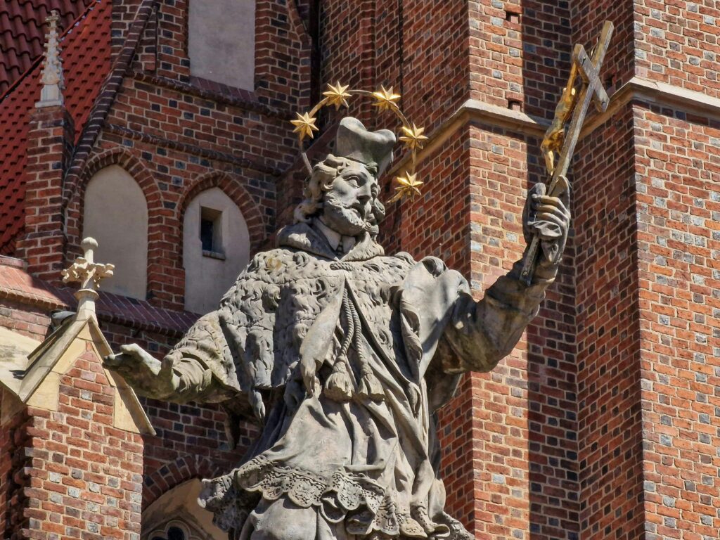 pexels-photo-24030885-24030885 Close-up of St. John Nepomuk statue against brick church in Wrocław, Poland.