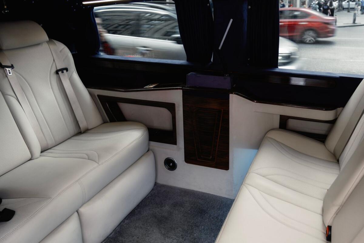 about-details Interior view of a luxury limousine showcasing white leather seating with stylish design and amenities.