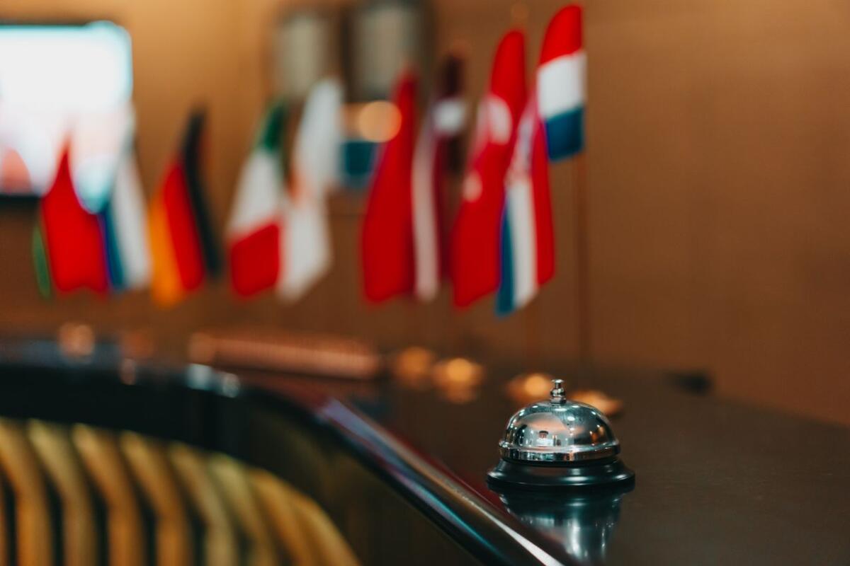 services-hero Sophisticated hotel lobby with a reception bell and array of international flags in focus.